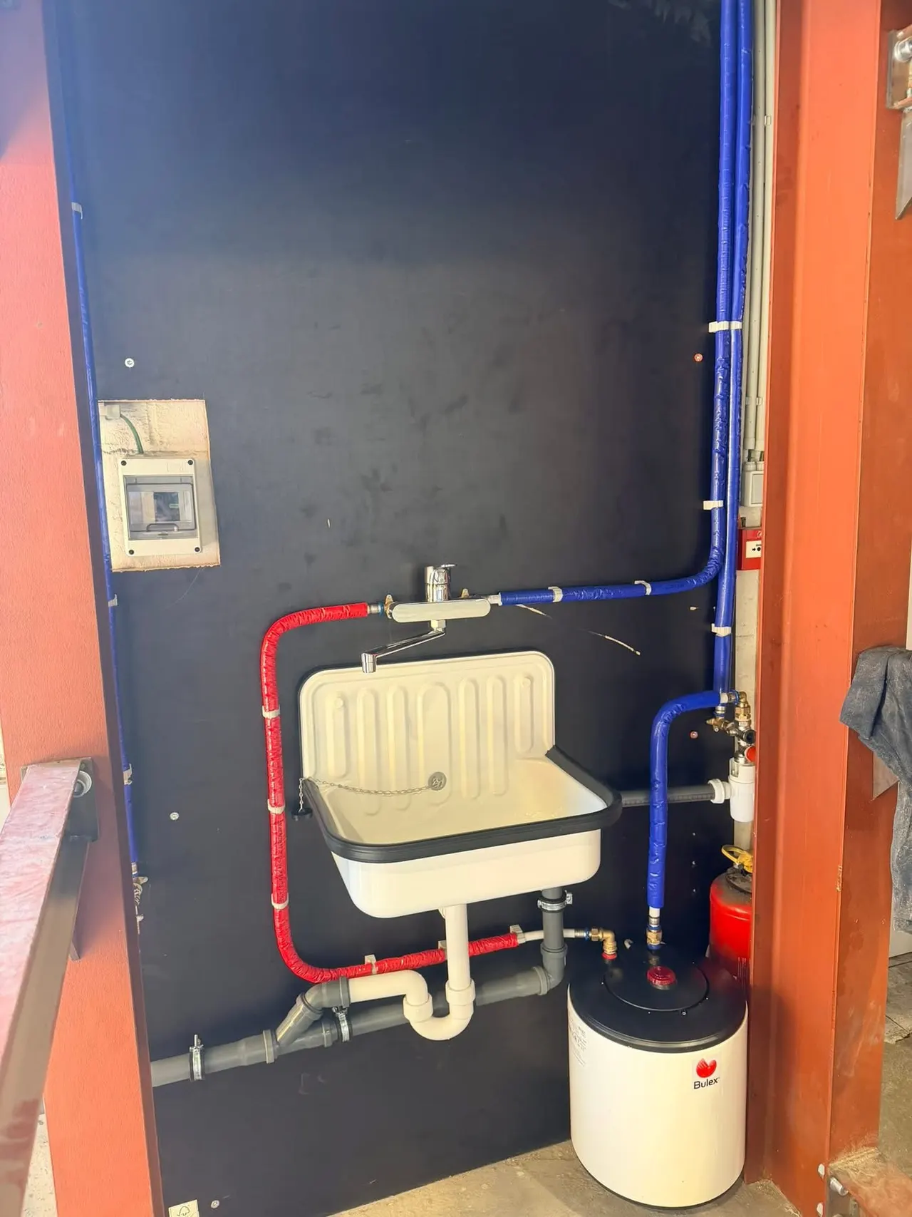 Évier d’atelier alimenté en eau de pluie, avec boiler électrique et conduites isolées rouge et bleu